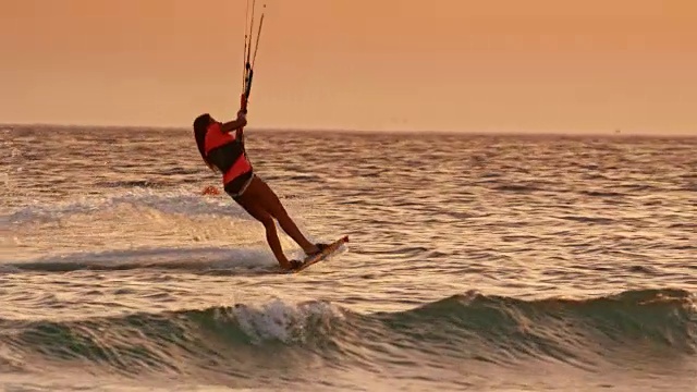 SLO MO女人骑她的风筝板和做一个跳跃在日落视频素材