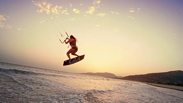 SLO MO女性风筝滑板在日落时加速跳跃视频素材