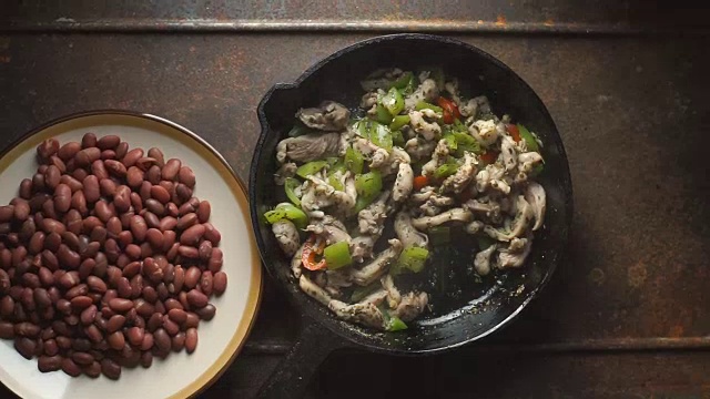 将豆子、辣椒和鸡肉撒在煎锅里。视频视频素材