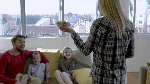 快乐的一家人吃着零食，享受着在家的时光。视频素材