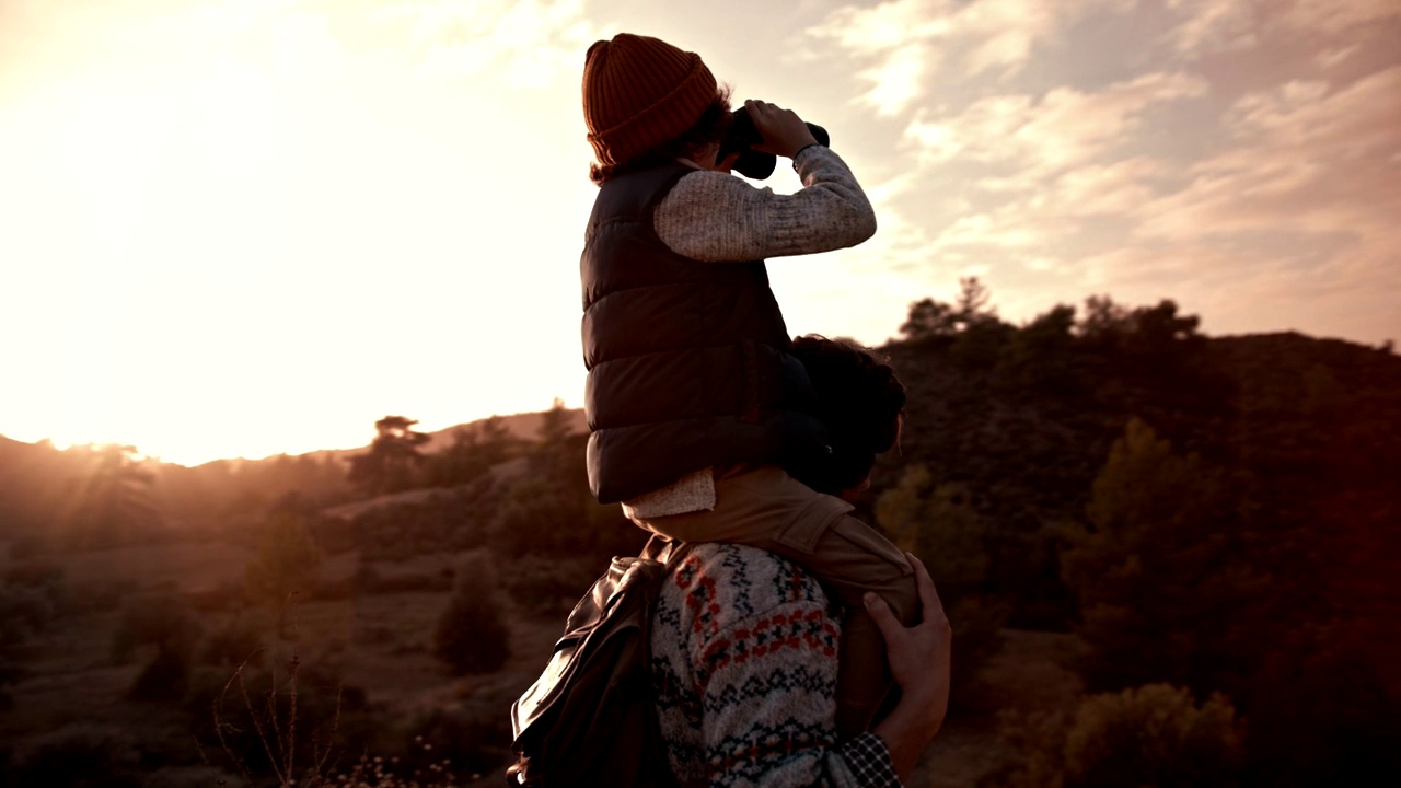 男孩骑在父亲的肩膀上，用双筒望远镜看风景视频下载