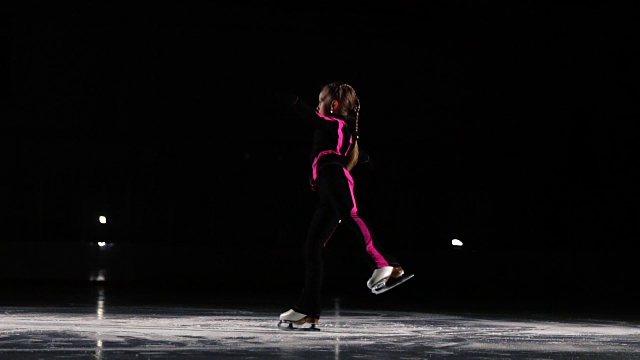一名专业的滑冰运动员在冰上的空中旋转着表演跳跃动作。花样滑冰比赛中的三周半跳视频素材