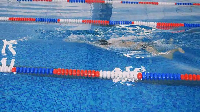 女游泳运动员在水下以慢动作运动。视频素材