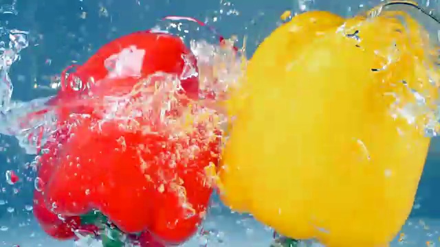 一个红辣椒和一个黄辣椒掉进水里。视频下载