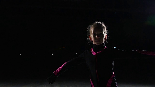 溜冰女孩穿着冰鞋进入镜头，直视镜头。触控笔上的摄像头在移动过程中也会跟着移动。冰上竞技场的背光视频素材