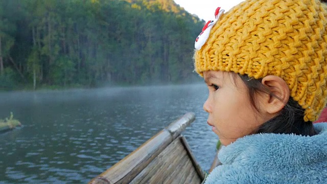 一个可爱的小女孩在竹筏上通过雾漂浮在湖面上在早上，在泰国Mae Hong Son视频购买