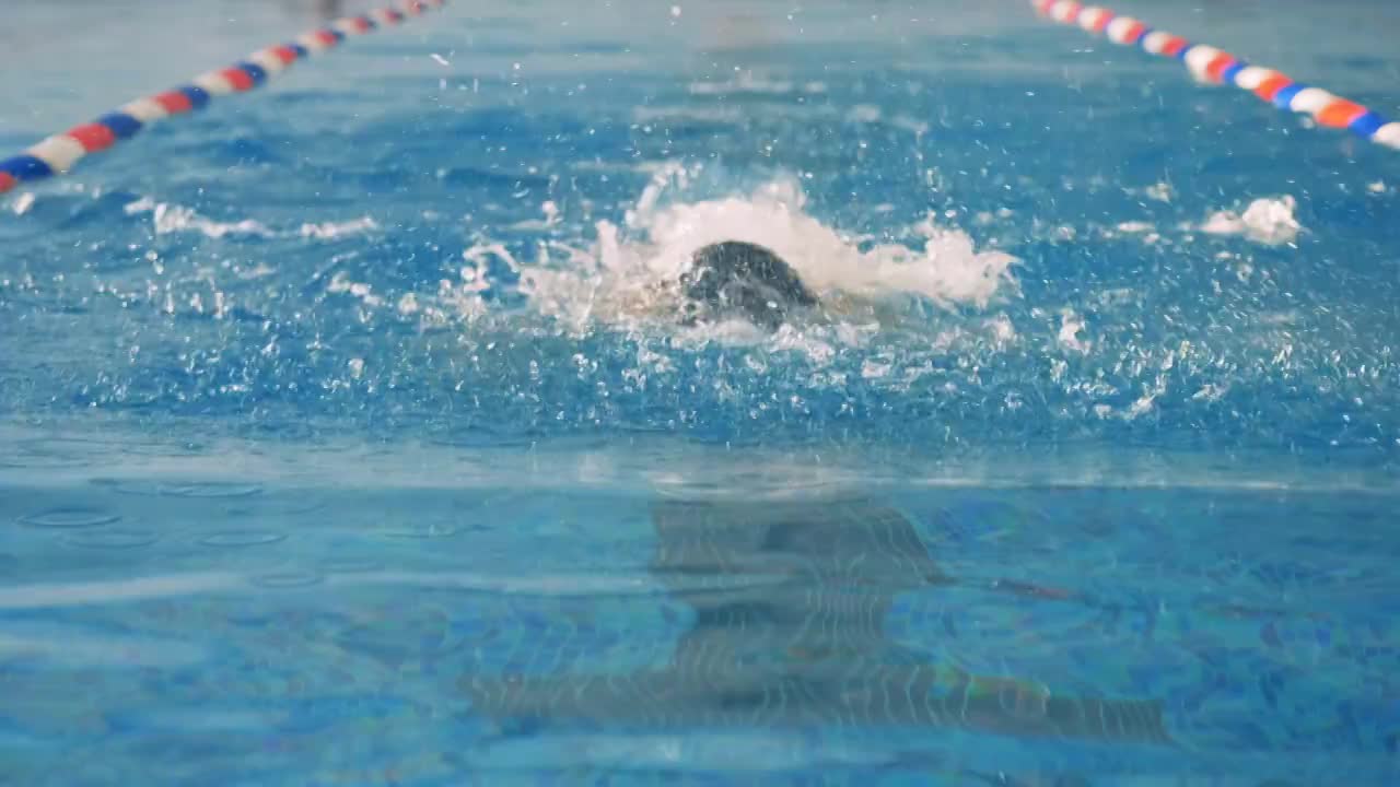 一位女游泳运动员用慢动作搅动水面。视频素材