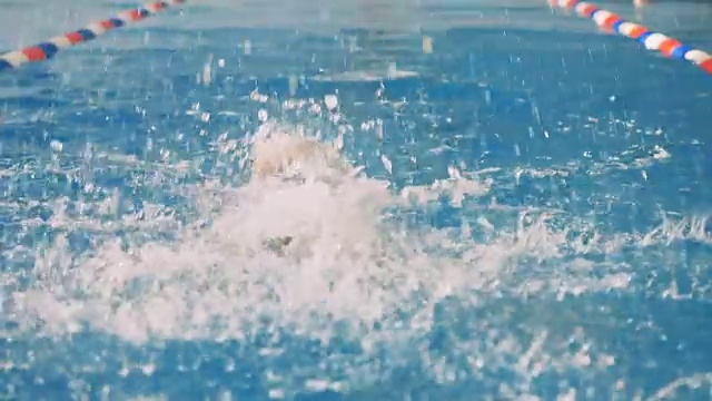 一名女性游泳运动员的动作是将头在水里和出水。视频素材