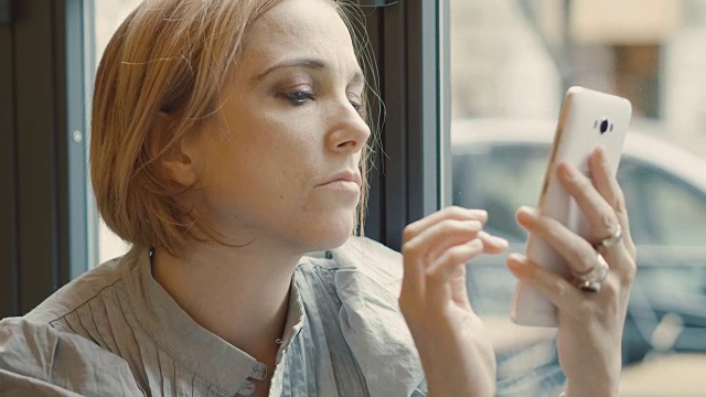 一个沉思的女人在自助餐厅等着看手机上的新信息视频素材