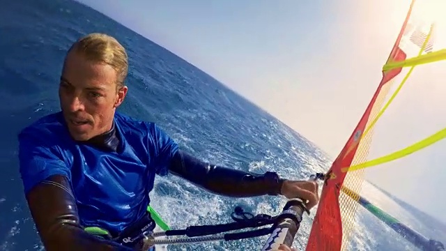 一名男性风帆冲浪者在阳光下骑行时亲吻相机视频素材