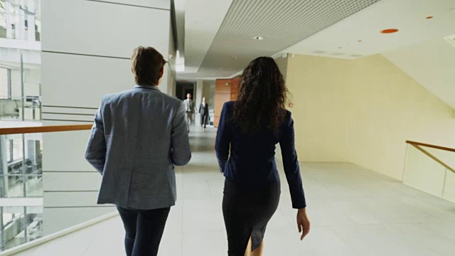 在现代商业中心里，女商人和女商人在大厅里走路，和同事开会，一起进电梯的跟踪拍摄视频素材