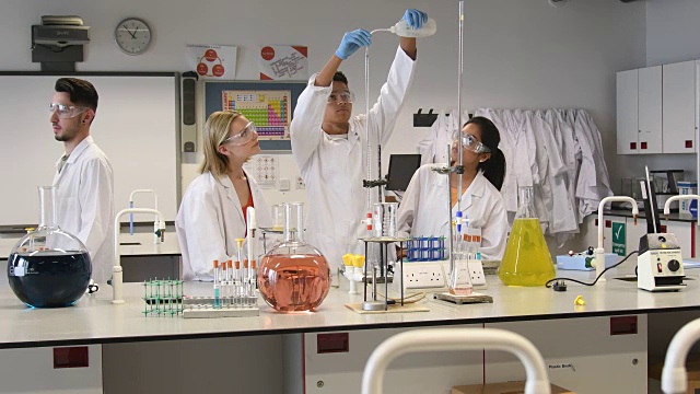 年轻男女在大学里和他们的老师一起做化学实验视频素材