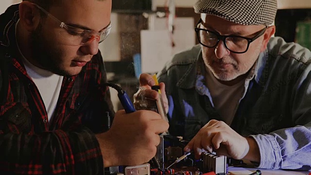 两个男工程师试图通过焊接来修复电路…视频素材
