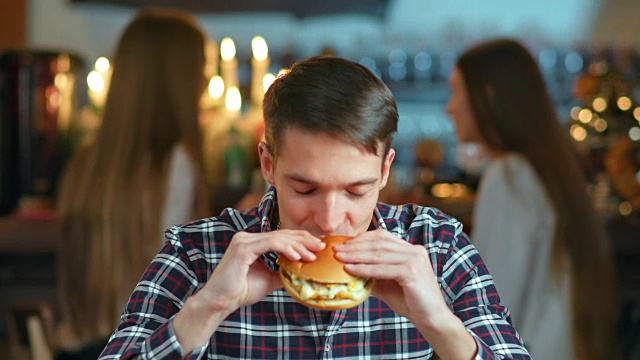 一个男人在餐馆里吃着汉堡包，面带微笑视频素材
