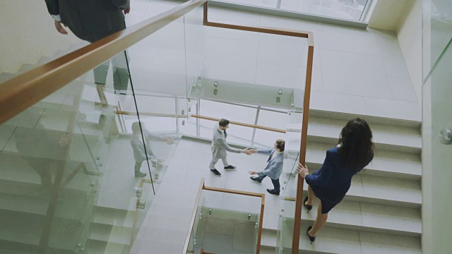 上图是两位商人在现代办公中心的楼梯上碰面，女同事在楼梯上交谈视频素材