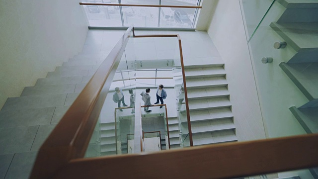 俯视两个商人在现代办公中心的楼梯上见面，在休息时交谈视频素材
