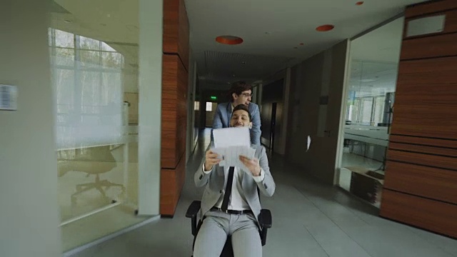 在现代商业中心的大厅里，两个疯狂的商人坐在办公椅上，把文件扔在地上视频下载