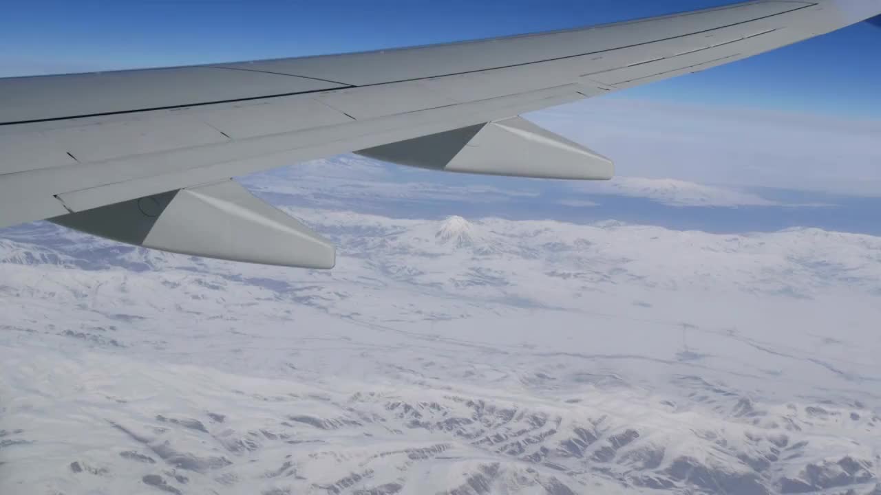 令人惊叹的美丽的山脉，略微覆盖着雪，掠过的云，从飞机窗口的景色视频素材