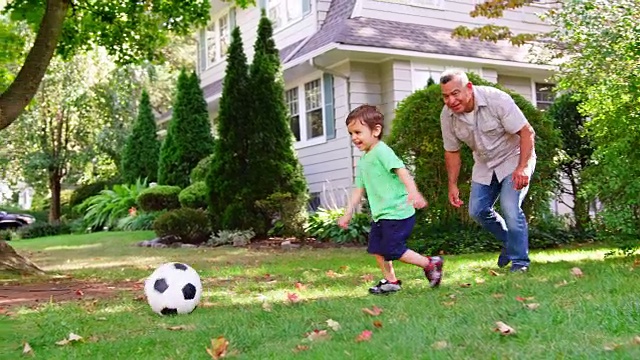 爷爷和孙子在花园里踢足球视频素材