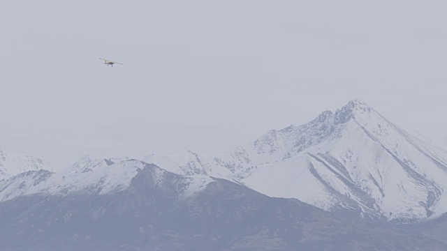 跟踪拍摄的一个飞行的小飞机与山的背景视频素材