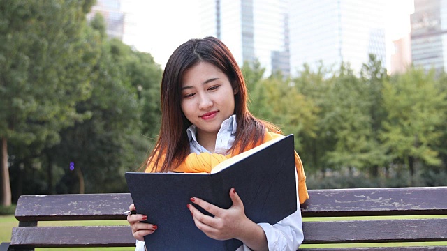 4K:美丽的亚洲女人在公园里读书，上海，中国视频下载