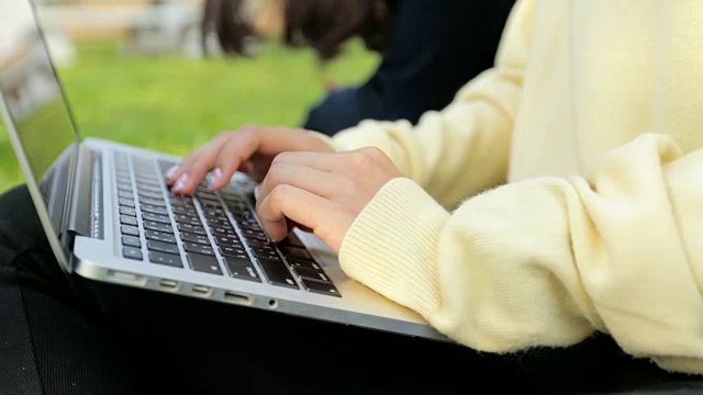 特写的女人的手打字在草地上的笔记本电脑视频下载