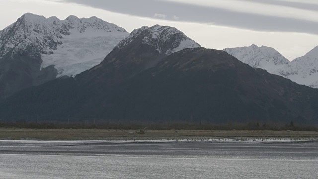 在北极国家野生动物保护区的水流后面的山脉的中景视频下载