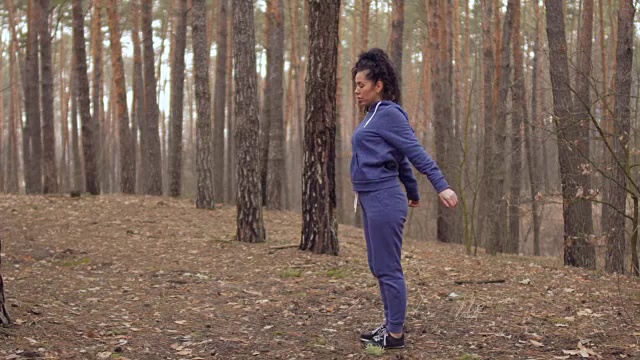 穿着运动服的年轻女子在森林里做手部运动视频下载