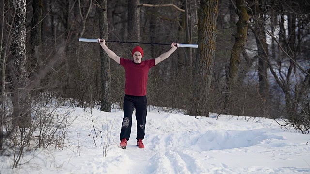 清晨，一个年轻的运动员把标竿举过头顶，在一片冰雪覆盖的冬日森林里用双腿向前冲刺视频素材