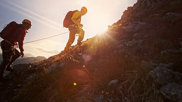 两名登山队员组成的绳索队在夕阳下爬山视频素材