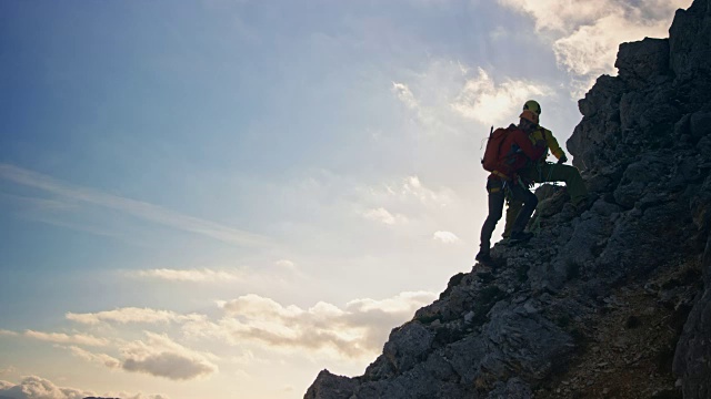 两个登山运动员在山顶下的阳光下握手视频下载