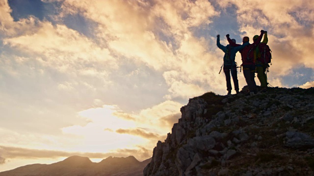 三个登山者在日落时分在山顶击掌视频素材
