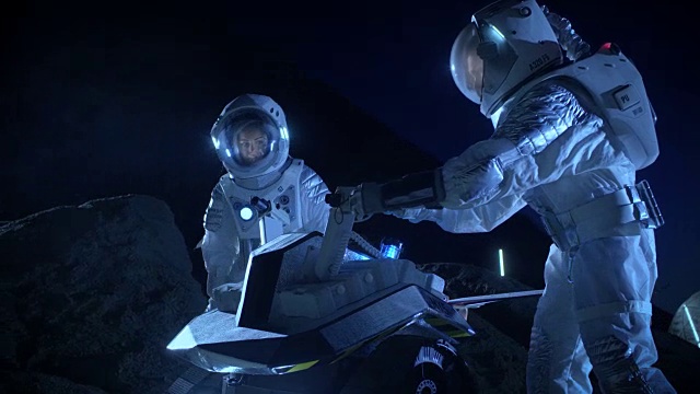 两名宇航员穿着宇航服在外星球上为表面探索任务准备太空车。关于太空殖民的未来概念。视频素材