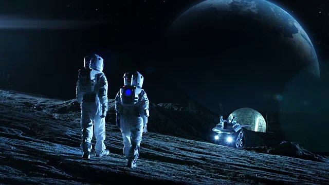 两名宇航员穿着太空服站在月球上看美丽的地球。在背景月球基地与测量圆顶。月球殖民和太空旅行概念。远景。视频素材