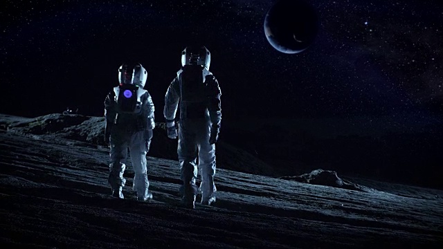 两名宇航员穿着太空服站在外星，观察这颗可能适宜居住的行星。月球殖民和太空旅行的高科技概念。视频素材