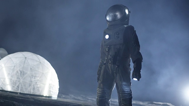 勇敢的宇航员穿着太空服手持手电筒，探索笼罩在烟雾中的外星球。冒险。星际空间旅行，宜居世界和地外殖民概念。视频素材
