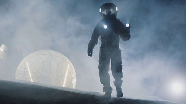 勇敢的宇航员穿着太空服拿着手电筒探索迷雾中的外星球。在背景生活的栖息地。太空旅行，宜居世界和殖民概念。视频素材