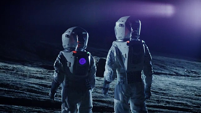 两名宇航员穿着太空服站在外星看黑暗的天空。太空旅行，宜居世界和殖民概念。视频素材