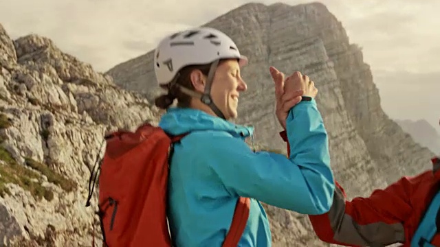 一名女性和两名男性登山运动员在登顶后在山顶击掌视频素材