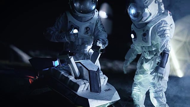 两名宇航员穿着宇航服在外星为火星表面探索探险准备太空车。太空旅行和太阳系殖民概念。视频素材
