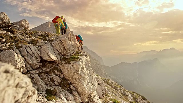 三个登山运动员在下午的阳光下到达山顶视频素材