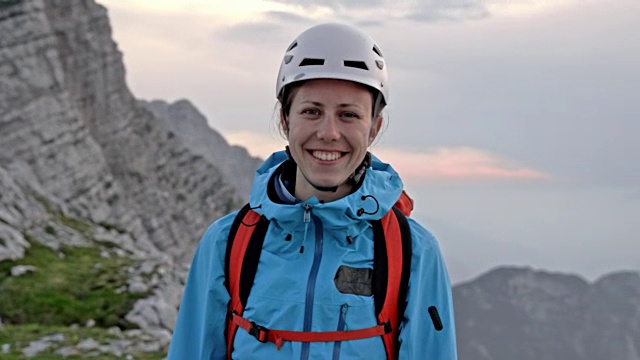 一位女登山运动员在日落时在山顶微笑的肖像视频素材