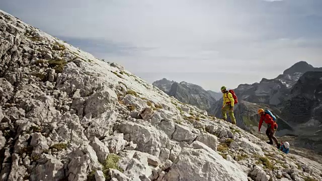 在阳光下攀登岩石斜坡的登山运动员视频下载