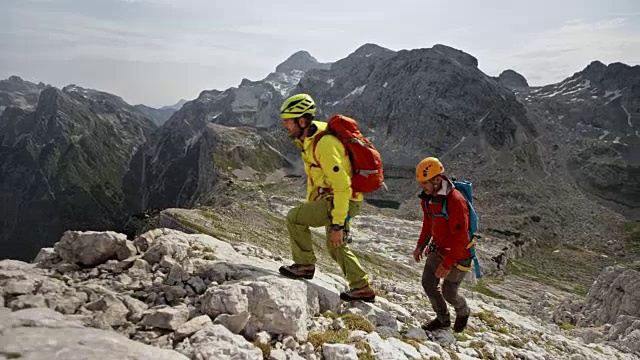 两名男性登山运动员在阳光下爬上山脊视频下载