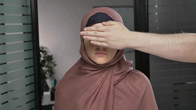 男人的手盖住女人的眼睛。穿着粉红色头巾的阿拉伯妇女。问题,侵权,恃强凌弱。看着相机，肖像。60 fps视频下载