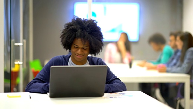年轻的非洲裔美国人在他的笔记本电脑上工作庆祝，看起来很兴奋视频素材