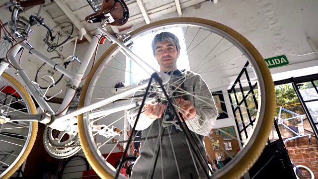 英俊的成年男子正在调整自行车后轮上的螺钉视频素材