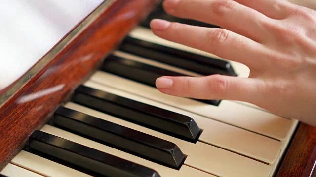 女性手指在复古钢琴键盘上弹奏琴键。景深浅。专注于钢琴琴键视频素材