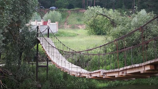 公园里的木桥。夹。通往雨林的绳索通道。穿过沼泽的旧木桥。悬在河上的木桥通向秋天的森林视频下载