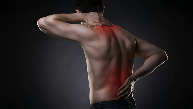 背部疼痛，背部疼痛的男人在黑色背景上视频素材